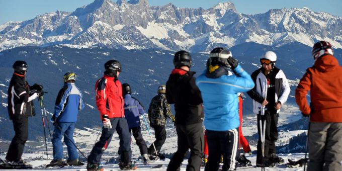 Skifahrer stehen auf einer Piste vor dem Dachsteinmassiv in Flachau. skifahren österreich