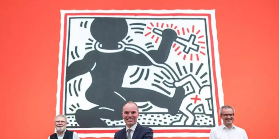 Rene Grohnert (l-r), Leiter Deutsches Plakat Museum, Peter Gorschlüter, Direktor Museum Folkwang, und Hans-Jürgen Lechtreck, stellvertrender Direktor Museum Folkwang, vor einem Bild von Keith Haring. Foto: Fabian Strauch/dpa