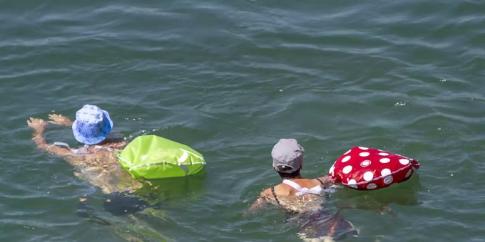 Badende mit bunten Schwimmsäcken lassen sich den Rhein in Basel hinunter treiben. (Symbolbild) Rhein