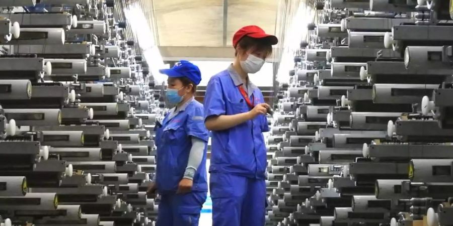 Arbeiter überprüfen eine Produktionslinie im Lianyungang Economic and Technological Development Area in Lianyungang in der ostchinesischen Provinz Jiangsu. Foto: Geng Yuhe/XinHua/dpa