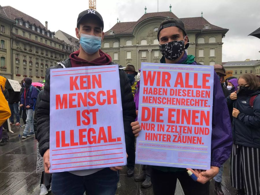 Demonstranten halten an der heutigen Demo auf dem Bundesplatz ihre Plakate in die Kamera.