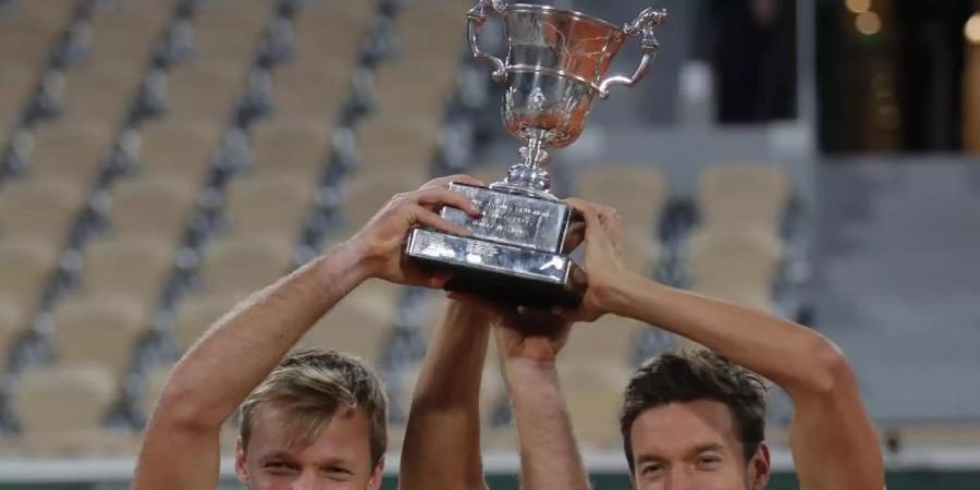 Kevin Krawietz (l) und Andreas Mies feiern mit der Trophäe den Finalsieg. Foto: Michel Euler/AP/dpa