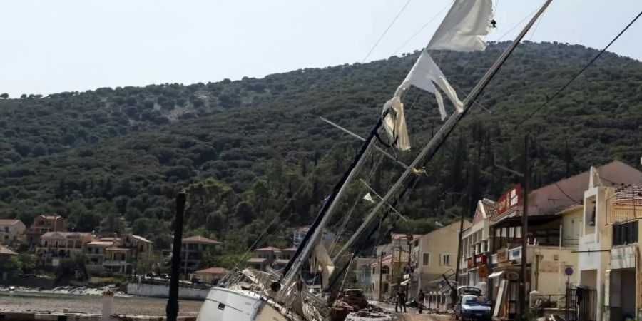 Eine Segelyacht liegt nach einem Sturm neben einer Strasse in Kefalonia. Der Wirbelsturm «Ianos» im Westen und ein weiteres Sturmtief über der Nordägäis hatten am Freitag und Samstag in weiten Teilen Griechenlands schwere Schäden verursacht. Foto: Nikiforos Stamenis/AP/dpa