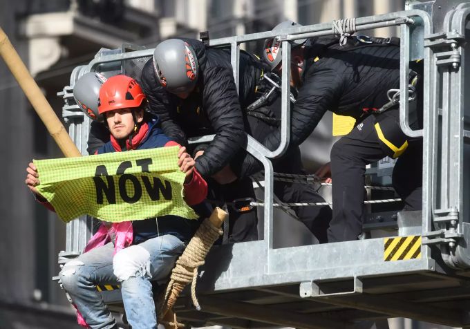 Polizisten entfernen einen Demonstrant, der sich auf einer Bambusstruktur niedergelassen hat. Extinction Rebellion - London