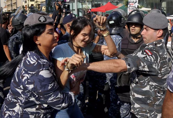 Polizisten ziehen eine regierungskritische Demonstrantin während einer Straßenblockade von Demonstranten von einer Hauptstrasse. libanon