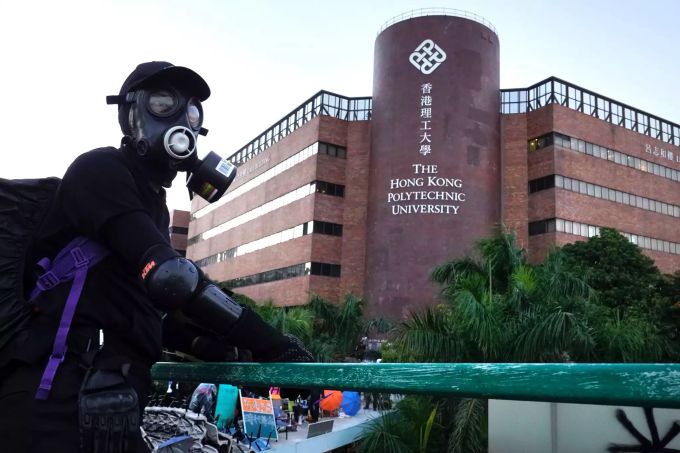 Ein Demonstrant mit einer Maske steht auf einer Brücke vor der Polytechnischen University. Hongkong