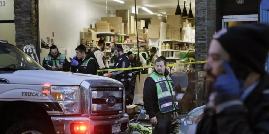 Rettungskräfte arbeiten in dem koscheren Supermarkt, wo bei einem stundenlangen Schusswechsel sechs Menschen starben. Foto: Seth Wenig/AP/dpa