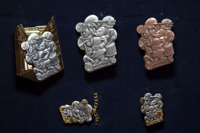 Die Basler Fasnachts-Plakette 2020 des Plakettenkünstlers Kurt Walter in der Ausführung Gold, Silber, Kupfer, Bijou und als Anhänger (im Uhrzeigersinn). Basler Fasnacht