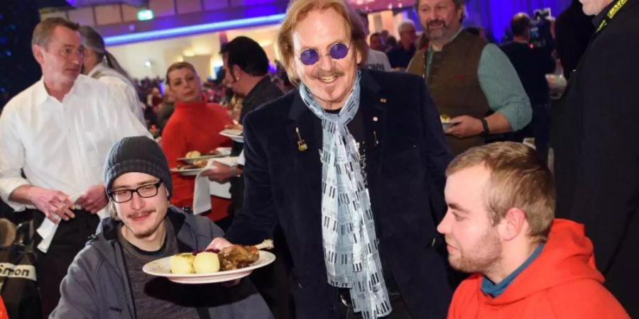 Musiker Frank Zander (M) verteilt bei seinem 25. Weihnachtsfest für Obdachlose und Bedürftige Weihnachtsgans an die Gäste. Foto: Gregor Fischer/dpa