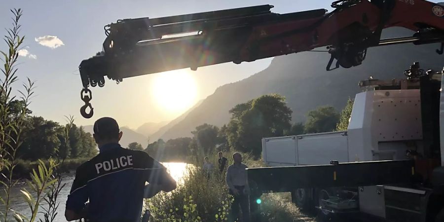 Walliser Kantonspolizisten bei der Bergung des Autowracks aus der Rhone. Nun steht fest, dass im Auto ein Mann und ein Mädchen gesessen hatten, die seit einem Unwetter vermisst werden.