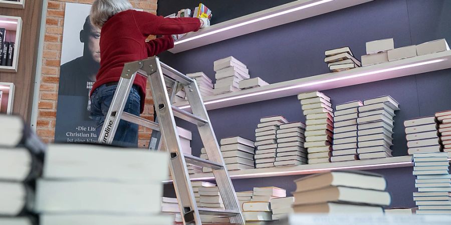 Eine Frau räumt vor der Eröffnung der Frankfurter Buchmesse Bücher ein. Foto: Sebastian Christoph Gollnow/dpa