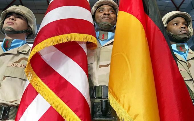 Drei Soldaten mit einer deutschen und einer amerikanischen Flagge stehen bei der Verabschiedung der 1. US-Infanteriedivision am Hauptquartier in Würzburg. US-Soldaten in Deutschland