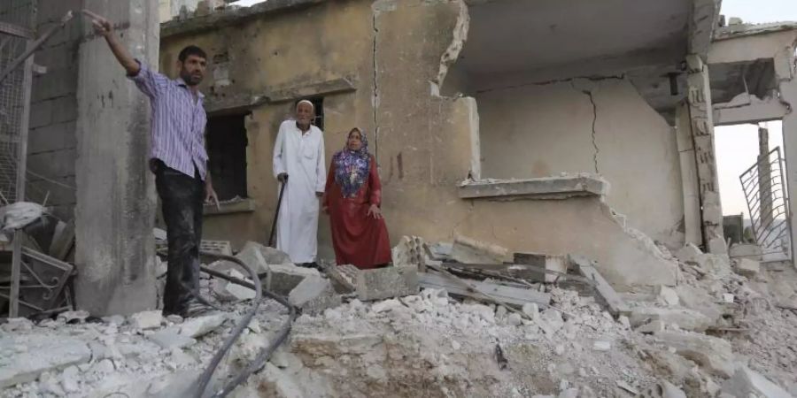 Bürger begutachten den Schaden an einem Haus, das bei Luftangriffen auf den Ort Muhambai zerstört wurde. Bei den Angriffen auf Syriens letztes grosses Rebellengebiet um die Stadt Idlib sind Aktivisten zufolge 13 Menschen getötet worden. Foto: Anas Alkharboutli