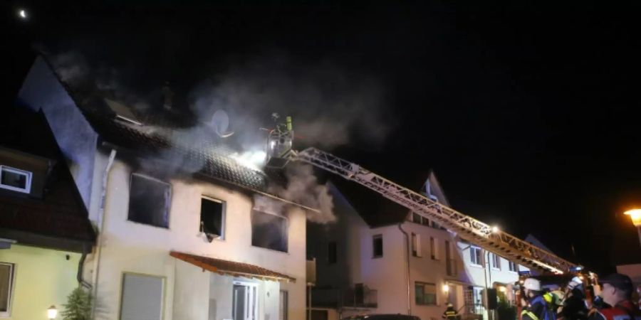 Einsatzkräfte an dem brennenden Haus