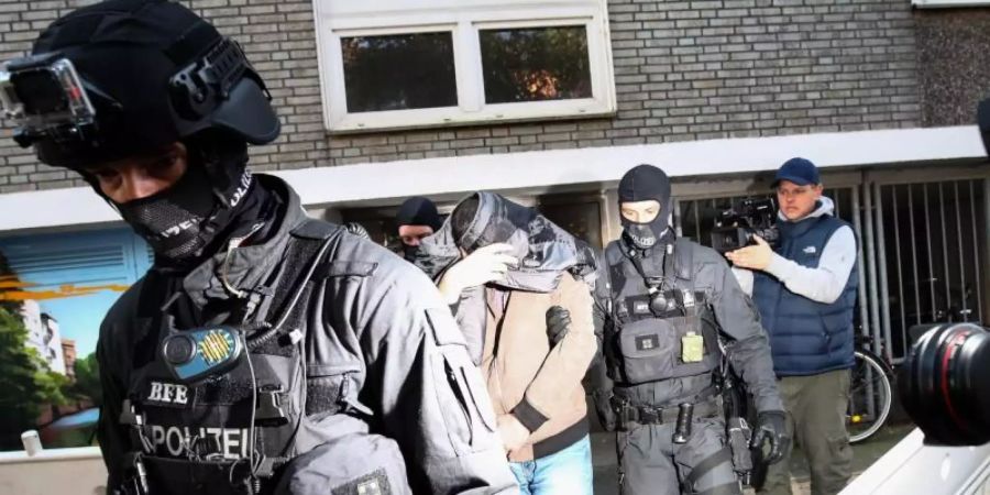 Terror-Razzia in Hamburg: Ein Mann wird von Polizisten aus einem Haus geführt. Foto: Christian Charisius