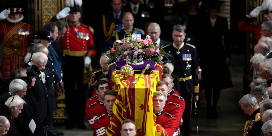 Mitglieder der königlichen Familie folgen dem Sarg von Königin Elizabeth II., der von mehreren Männern getragen wird.