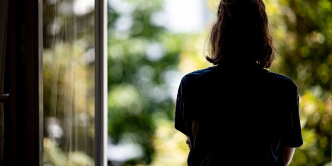 Eine Frau steht in ihrer Wohnung an einem Fenster. Die Zahl der Menschen, die sich wegen psychischer Erkrankungen krankmelden, nimmt zu. Eine Frau steht in ihrer Wohnung an einem Fenster. Die Zahl der Menschen, die sich wegen psychischer Erkrankungen krankmelden, nimmt zu.