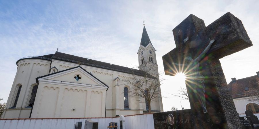 Das Kreuz eines Grabsteins steht vor der katholische Kirche St. Nikolaus in Garching.