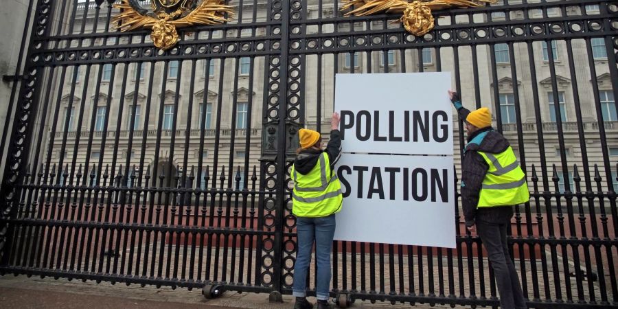 Anhänger der Kampagnengruppe Republic hängen ein Wahllokalschild ans Geländer des Buckingham Palace in London.