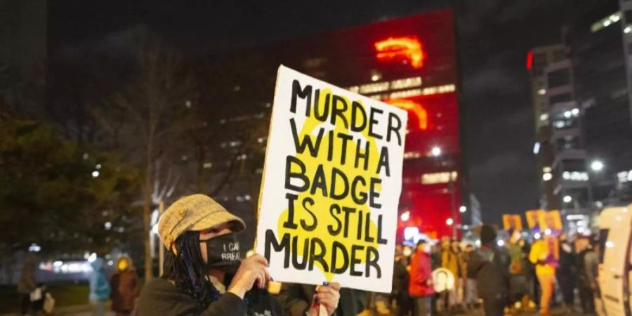 Eine Frau hält während eines Protests in Minneapolis ein Schild mit der Aufschrift «Murder with a badge is still murder» («Mord mit einer Dienstmarke ist immer noch Mord»). Foto: Henry Pan/ZUMA Wire/dpa