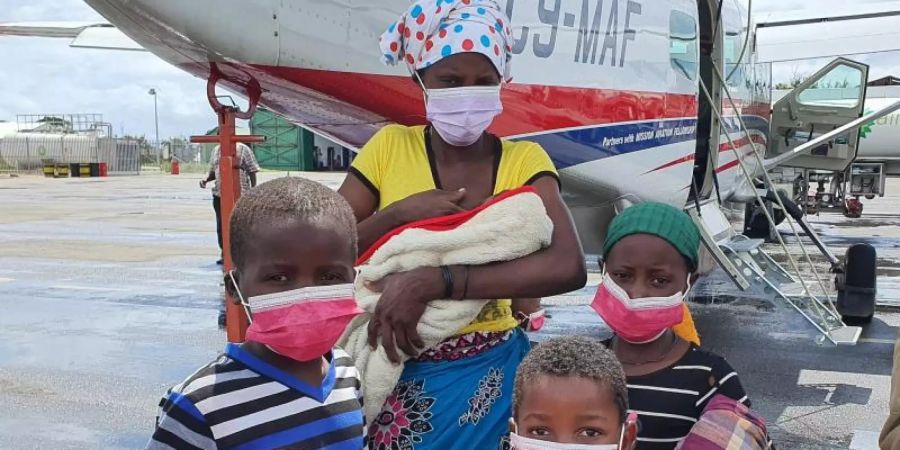 Eine Familie auf dem Rollfeld des Flughafens der Provinzhauptstadt Pemba. In Mosambik sind nach Angaben des Welternährungsprogramms (WFP) annähernd eine Million Menschen infolge von Terror und Gewalt vom Hunger bedroht. Foto: Dave Lepoidevin/Ambassador Aviation/AP/dpa