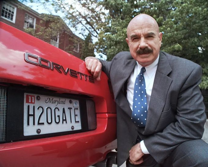 G. Gordon Liddy kniet neben seiner Corvette vor dem Radiosender in Fairfax, Virginia, wo er 1997 seine syndizierte Radiotalkshow ausstrahlt. Obit Liddy