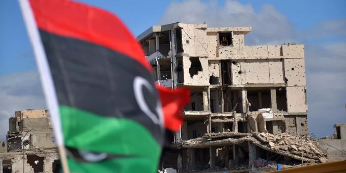 Die libysche Flagge wht vor einem zerstörten Gebäude. Lybien Attentat