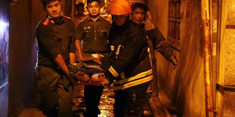 Rettungskräfte tragen eine Person aus einem brennenden Gebäude in der vietnamesischen Hauptstadt Hanoi.