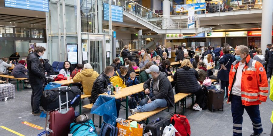 Geflüchtete aus der Ukraine sitzen nach der Ankunft im Flughafen Erfurt-Weimar und werden von Helfern betreut.