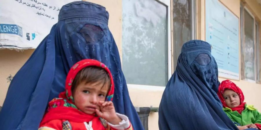 Zwei afghanische Frauen warten mit ihren Kindern vor einer Klinik für Ernährungsfragen. Foto: Julian Frank/WFP/dpa