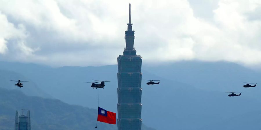 Ein Militärhubschrauber zieht eine riesige Taiwan-Fahne hinter sich her und fliegt vor den Feierlichkeiten des Nationalfeiertag am Hochhaus «Taipei 101» vorbei. Foto: Daniel Ceng Shou-Yi/ZUMA Press Wire/dpa