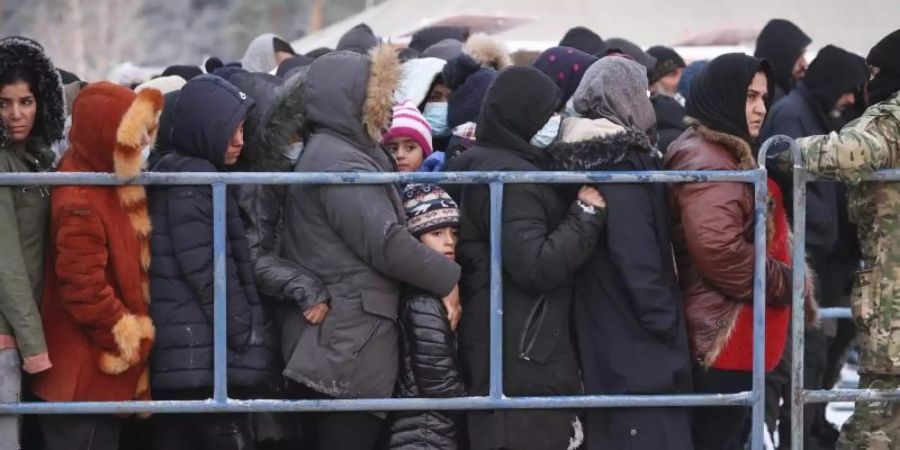 Das von der belarussischen Staatsagentur BelTA zur Verfügung gestellte Foto zeigt Migranten, die in einem Logistikzentrum an der belarussisch-polnischen Grenze für Essen anstehen. Foto: Oksana Manchuk/BelTA/AP/dpa