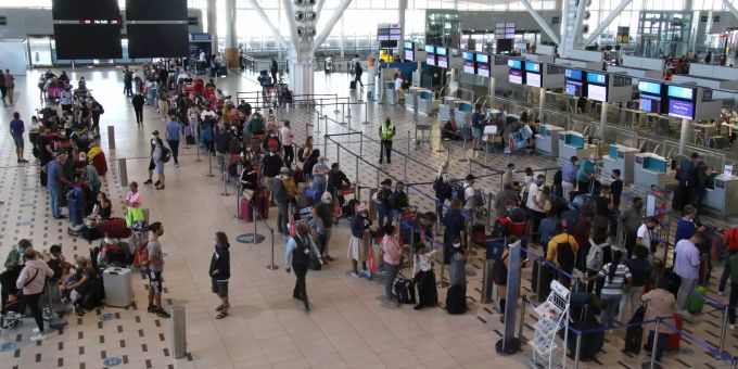 27.11.2021, Südafrika, Kapstadt: Reisende stehen am Flughafen in Kapstadt in langen Schlangen an den wenigen Schaltern an, die überhaupt noch offen sind. (Symbolbild) Reisende am Flughafen Kapstadt