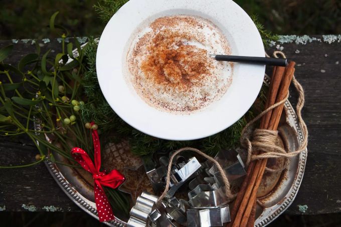 Mit Milchreis samt Zucker und Zimt kommt man in Finnland bereits am Morgen des 24. Dezember, also Heiligabend, in weihnachtliche Stimmung. Milchreis auf weissem Teller auf Metallblech mit Ausstechformen