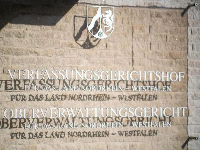 An der Aussenfassade am Oberverwaltungsgericht hängt eine Hinweistafel mit dem Landeswappen von NRW. Foto: Guido Kirchner/dpa An der Aussenfassade am Oberverwaltungsgericht hängt eine Hinweistafel mit dem Landeswappen von NRW. Foto: Guido Kirchner/dpa