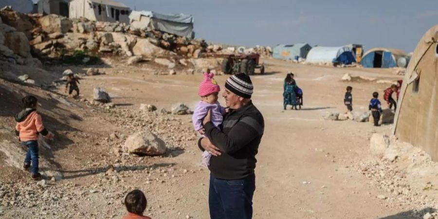 Ein Mann steht mit seinen Kindern in einem Flüchtlingslager in der Provinz Idlib. Foto: Anas Alkahrboutli/dpa/dpa