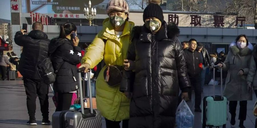 Wegen des chinesischen Neujahrsfests am 25. Januar startete in China bereits eine Reisewelle. Um sich nicht mit dem gefährlichen Coronavirus anzustecken, tragen viele Menschen einen Mundschutz. Foto: Mark Schiefelbein/AP/dpa