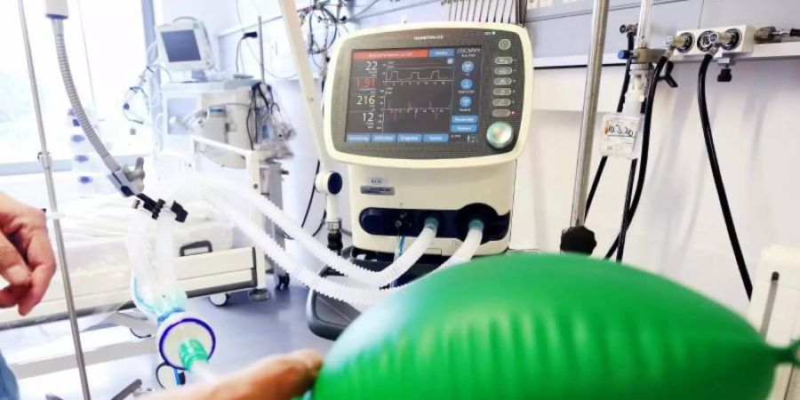 An einem Intensivbett für Corona-Patienten zeigt ein Arzt, die Funktionsweise eines Beatmungsgerätes. Foto: Roland Weihrauch/dpa
