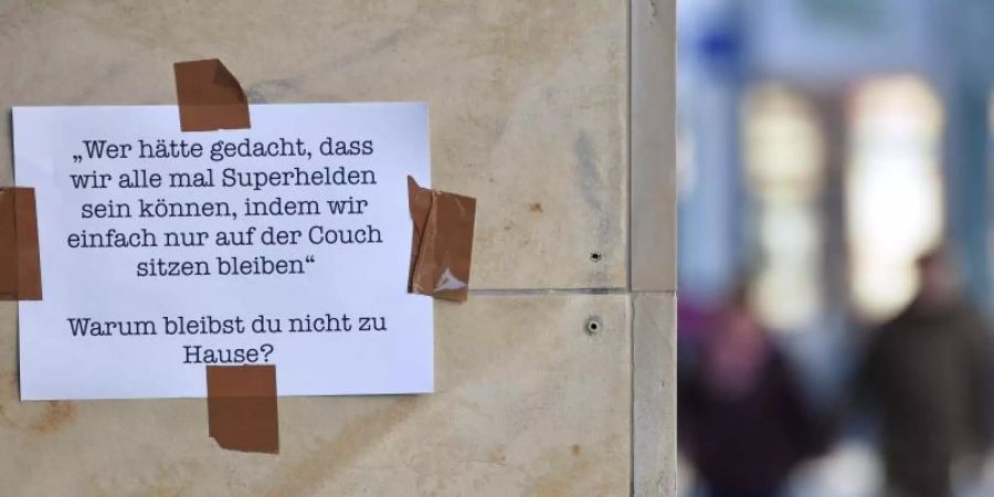 Botschaft auf einem Blatt Papier an einer Hauswand in Erfurt: "Warum bleibst Du nicht zu Hause?". Foto: Martin Schutt/dpa-Zentralbild/dpa