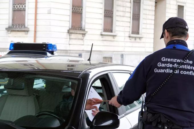 Ein Zollbeamter kontrolliert am schweizerisch-italienischen Grenzübergang die Papiere (Ausweis G) von Grenzgängern. Autoschlangen stehen vor den Schweizer Grenzern, die alle Papiere kontrollieren, seit die Italiener für das ganze Land weitreichende Ausgehsperren verhängt haben. Normalerweise werden hier an der Grenze nur gelegentliche Stichproben gemacht. Coronavirus - Schweizerisch-italienische Grenze