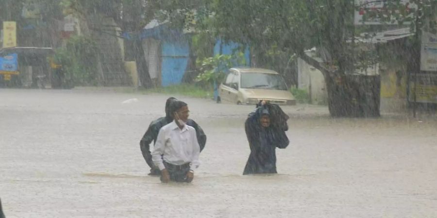 Menschen waten in Kolhapur durch das Hochwasser. Foto: Uncredited/AP/dpa