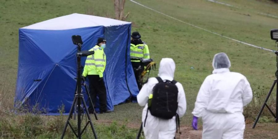 Zwei Gerichtsmediziner gehen zu einem Zelt am Tatort auf dem Bugs Bottom Feld. Fünf Jugendliche sollen hier im Januar einen 13-jährigen Jungen erstochen haben. Foto: Jonathan Brady/PA Wire/dpa