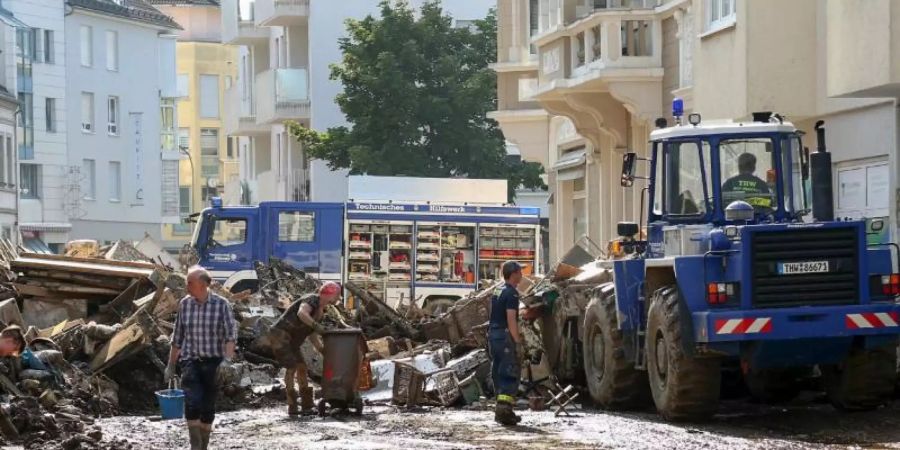 Mitarbeiter des Technischen Hilfswerks (THW) helfen bei Aufräumarbeiten nach der Unwetterkatastrophe in einer verschlammten Strasse. Foto: Alexander Mann/THW/dpa