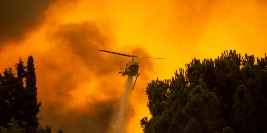 Helikopter mit Löschwasser über Waldbrand bei Athen