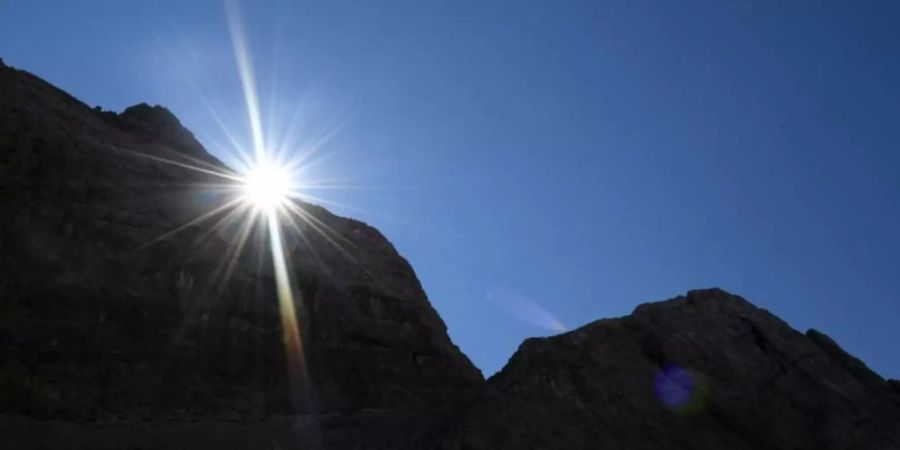 Die Sonne kommt am Morgen hinter einem Felsen im Watzmannkar (Bayern) hervor. Foto: Angelika Warmuth/dpa