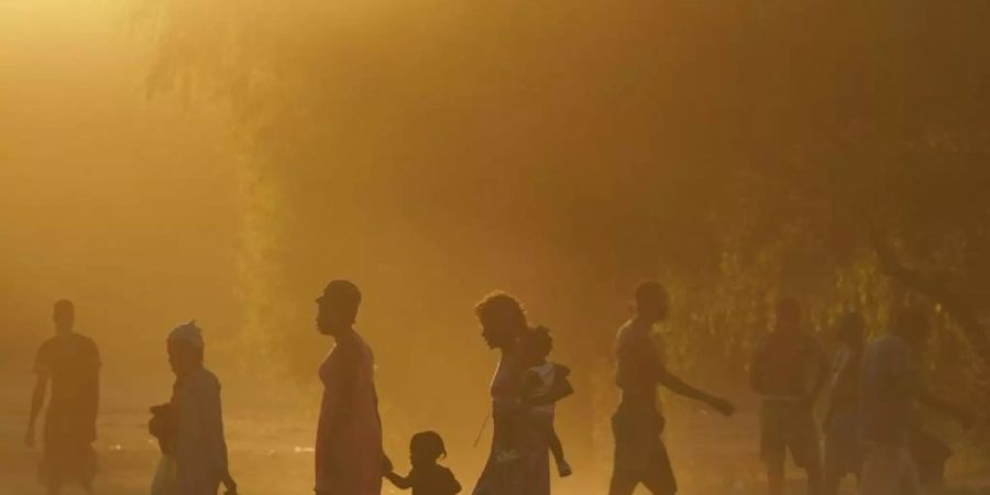 Migranten, viele von ihnen aus Haiti, gehen zu einem improvisierten Flüchtlingslager in Ciudad Acuña. Foto: Fernando Llano/AP/dpa