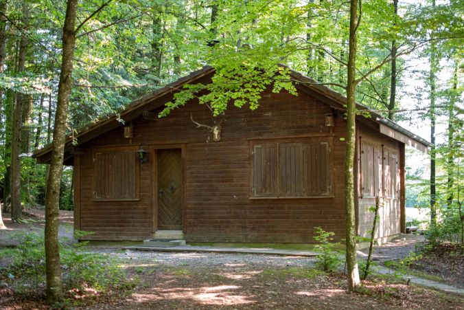 Eine grosse Waldhütte steht neben dem Grillplatz.