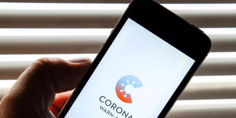 Auf dem Bildschirm eines Apple iPhone SE ist der vom Presse- und Informationsamt der Bundesregierung herausgegebene Startschirm einer Corona Warn-App abgebildet. Foto: Stefan Jaitner/dpa