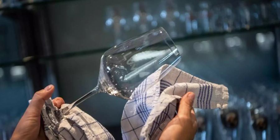 Vorbereitung auf die Gäste: In einem Restaurant werden die Gläser poliert. Foto: Sina Schuldt/dpa