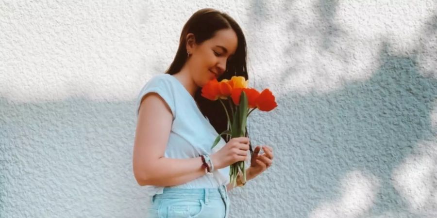 Eine Frau riecht an einem Strauss Tulpen
